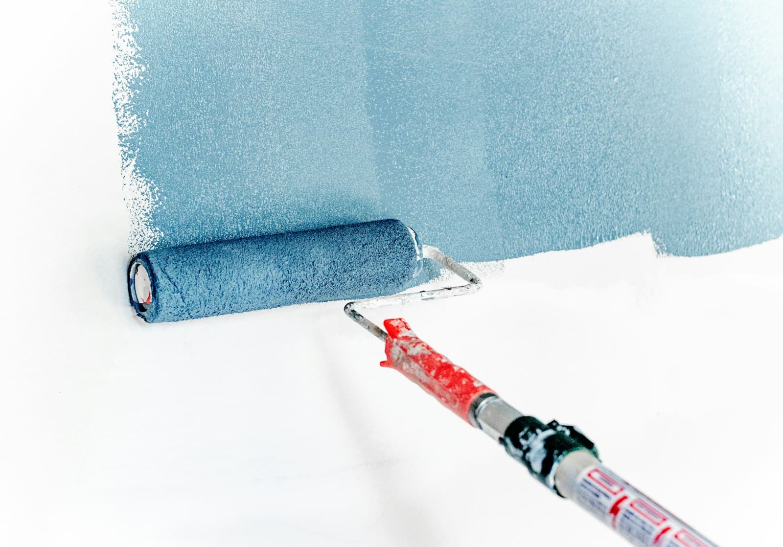 Painter rolling blue paint onto a wall